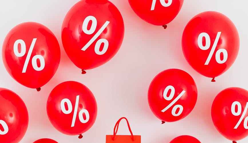 a red paper bag in the middle of red balloons with percentage symbols