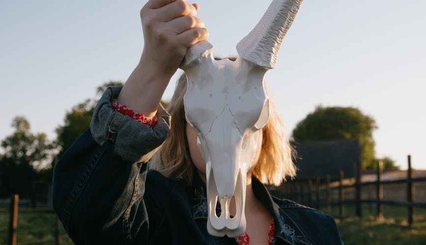 faceless woman with bull skull in countryside